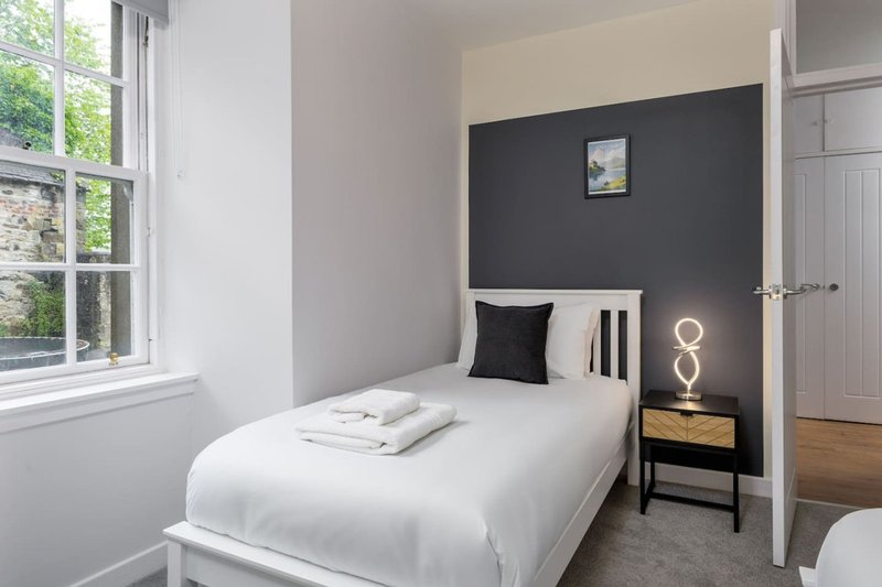 Modern bedroom with single bed, dark accent wall, bedside table and window