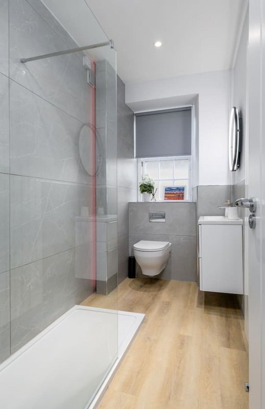 Modern bathroom with walk-in shower, toilet, sink and wooden floor