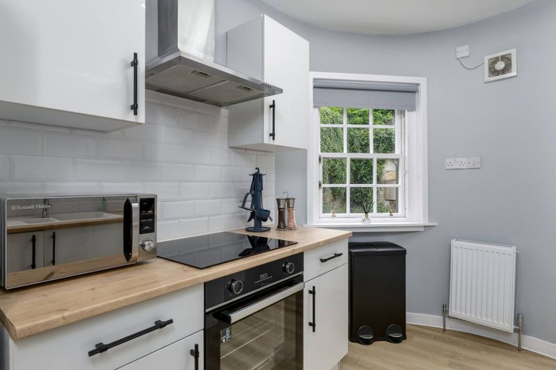 Modern kitchen with white cabinetry, wooden countertop, black oven and stainless steel appliances