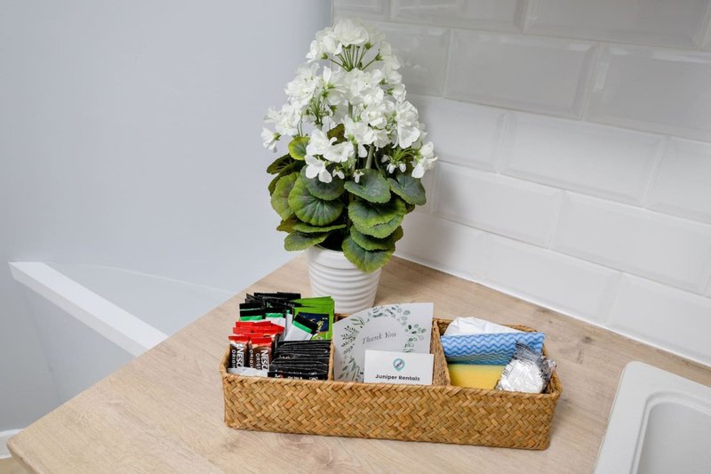 Bathroom counter with white potted flowers, wicker basket containing toiletries and supplies