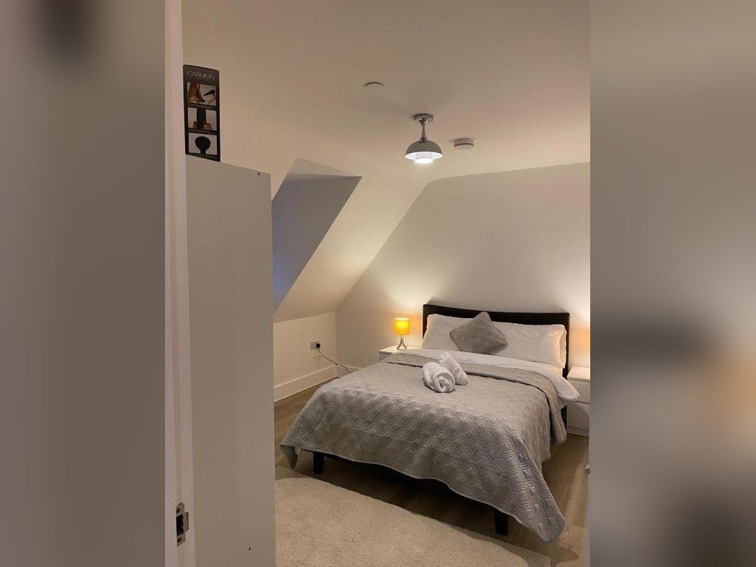 Attic bedroom with double bed, grey bedding, pendant lights and sloped ceiling