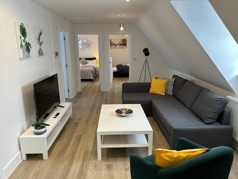 Modern loft living room with gray sofa, white coffee table, TV stand, and yellow accent cushions