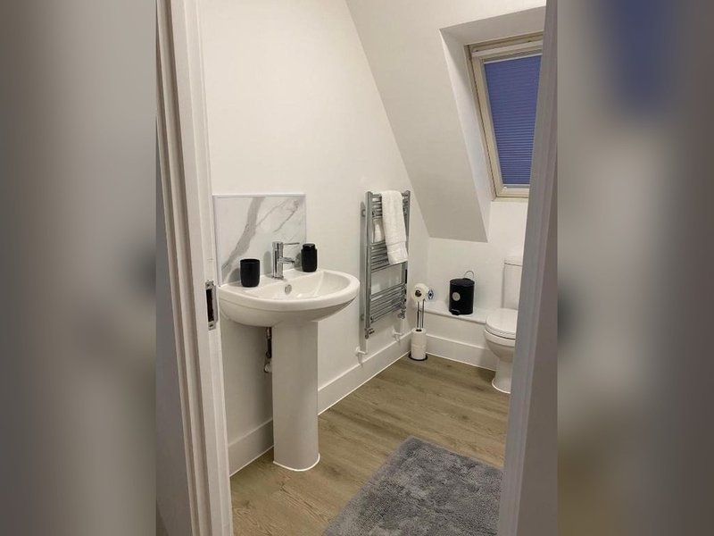 Modern bathroom with pedestal sink, heated towel rail, mirror and window