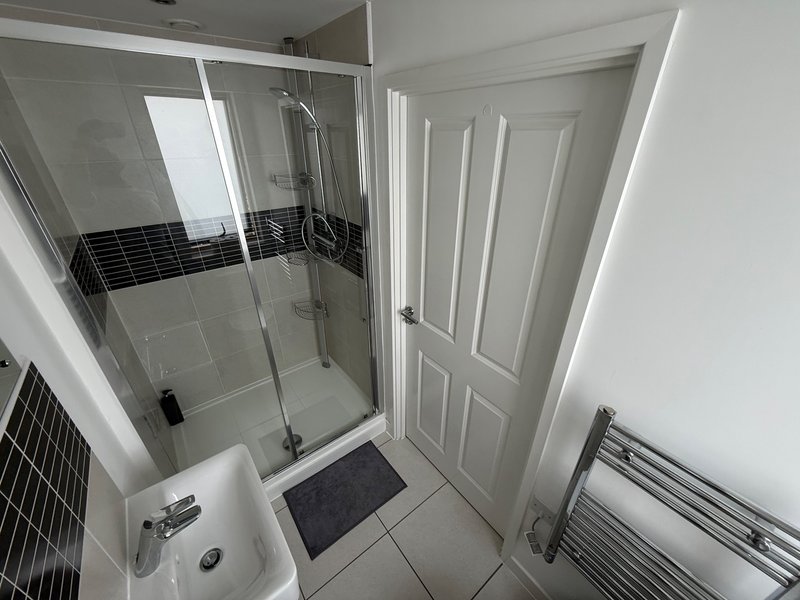 Modern bathroom with walk-in shower, white tiles, and heated towel rail