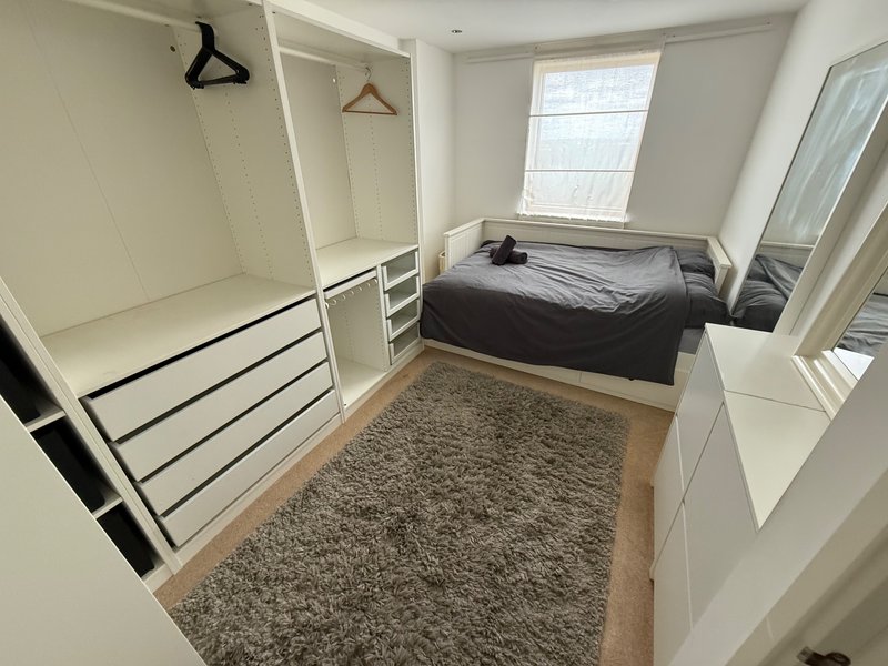 Bedroom with double bed, fitted wardrobes, grey rug and natural light from window