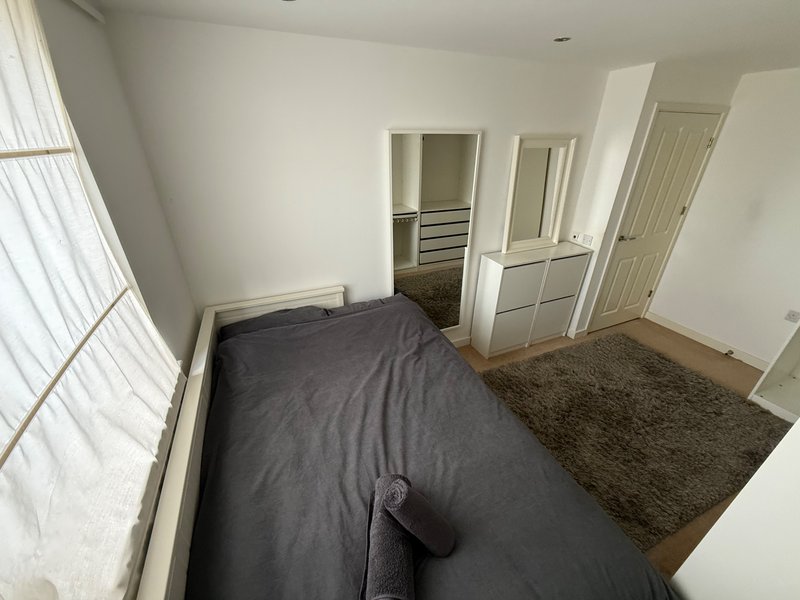 Bedroom with double bed, dark bedding, wardrobe, and window with vertical blinds