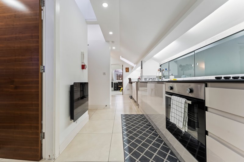 Modern galley kitchen with white cabinetry, stainless steel appliances, and patterned floor runner
