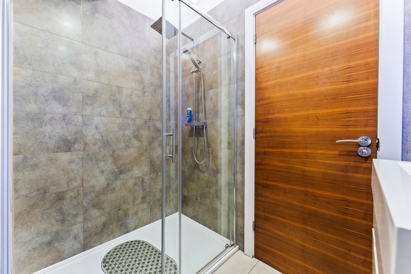 Modern bathroom with glass shower enclosure, tiled walls, and wooden door