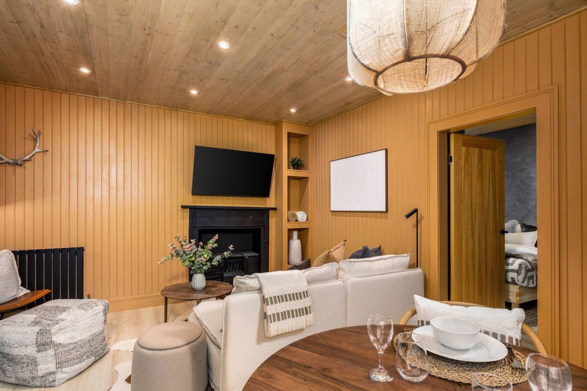 Warm wooden interior with cream sofa, dining table, fireplace and flat-screen TV
