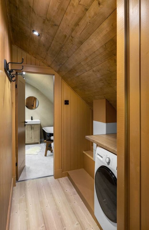 Wooden hallway with washing machine, leading to bathroom with sink and toilet