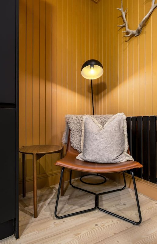 Modern interior corner with wooden paneling, mid-century chair, cushion, floor lamp and side table