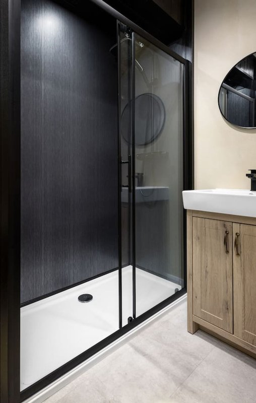Modern bathroom with black-framed shower enclosure, white basin and wooden vanity