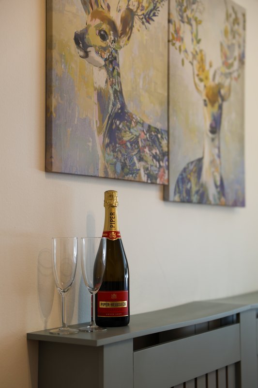 Modern sideboard with champagne bottle, glasses, and framed floral artwork on wall
