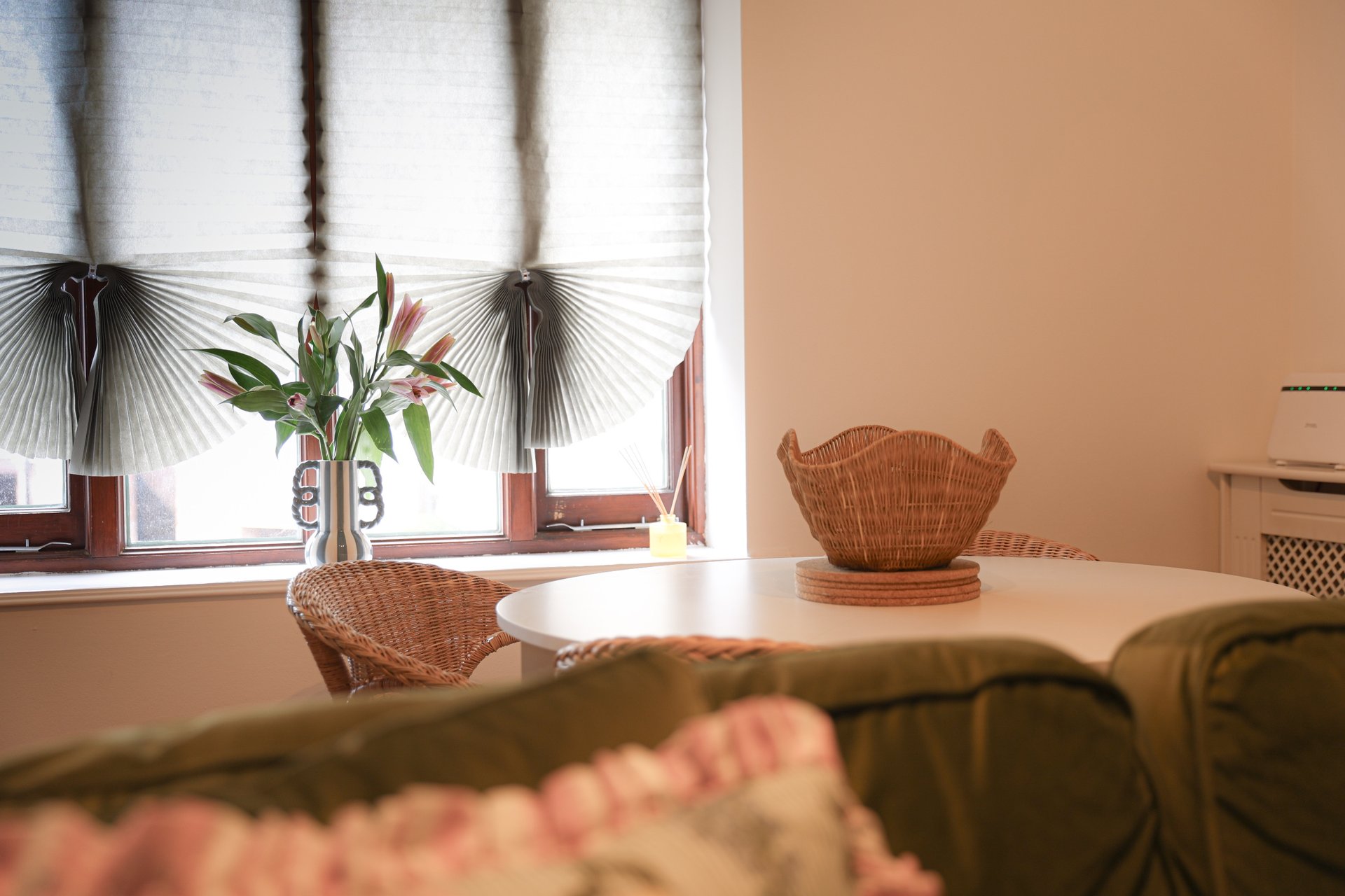 Dining area with table, wicker chairs, window with plants and decorative fans