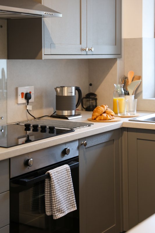 Modern kitchen with dark cabinetry, stainless steel appliances, and breakfast items on counter