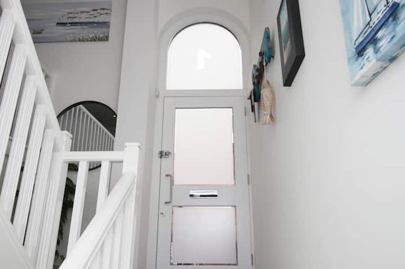 Bright hallway with white walls, arched doorway, staircase and framed artwork