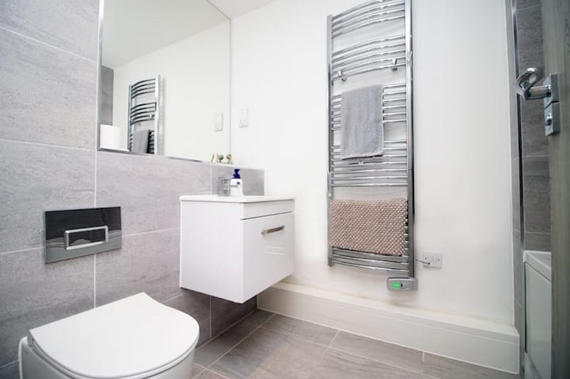 Modern bathroom with toilet, white vanity sink, heated towel rail and shower enclosure.