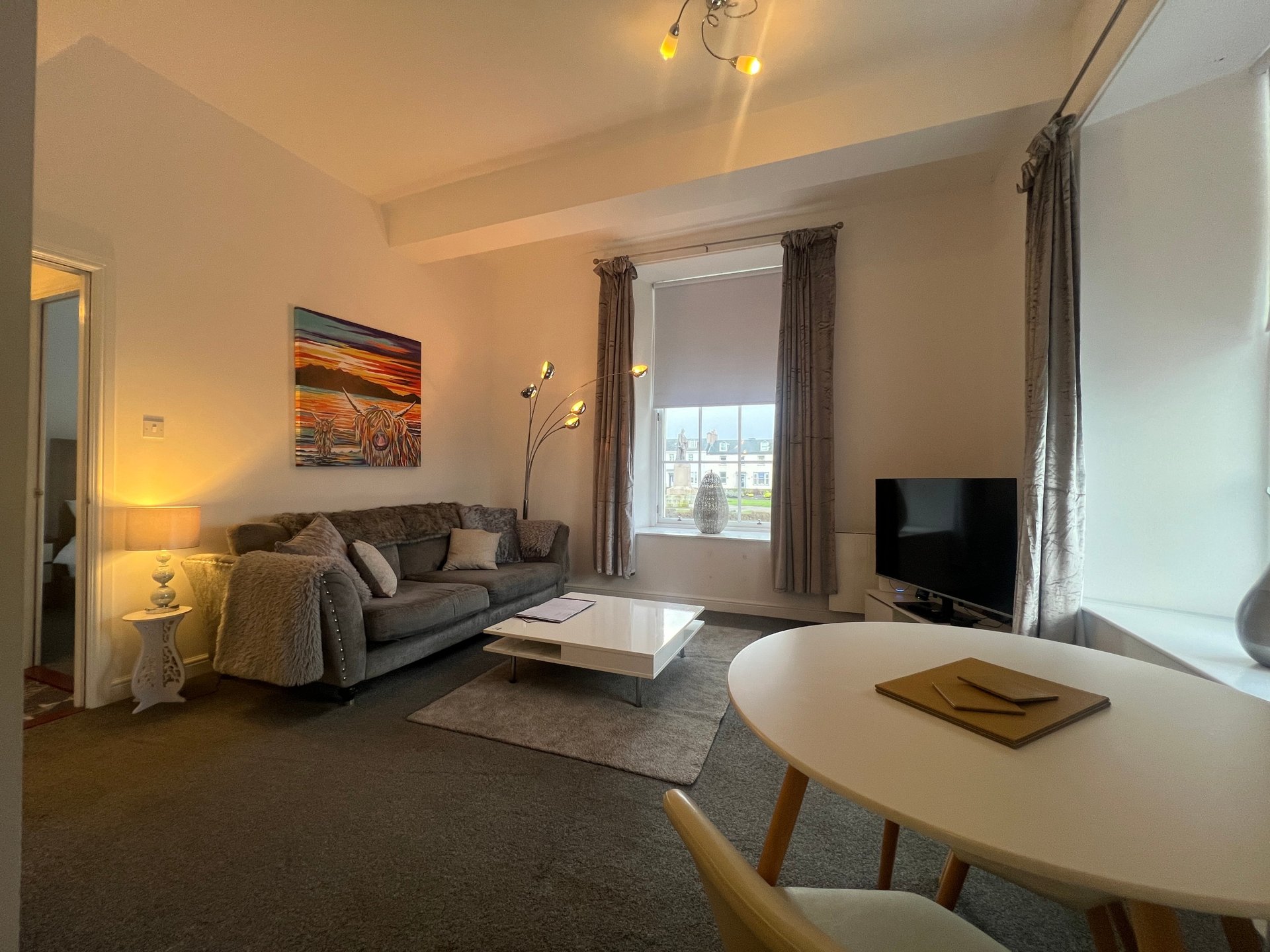 Modern living room with sofa, TV, dining table and window with city view