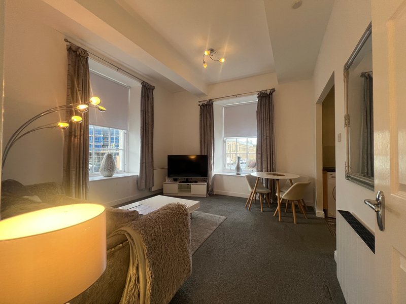 Spacious studio apartment with bed, seating area, desk, windows and modern lighting