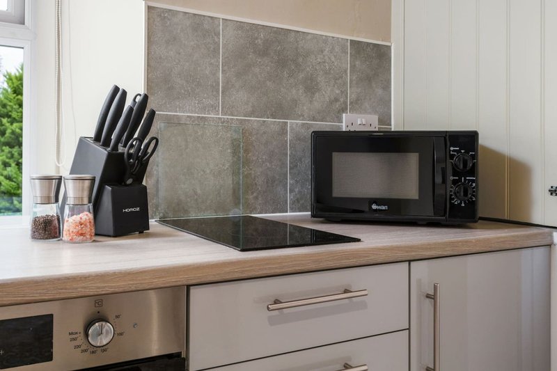 Modern kitchen with grey tile backsplash, microwave, knife block and countertop appliances