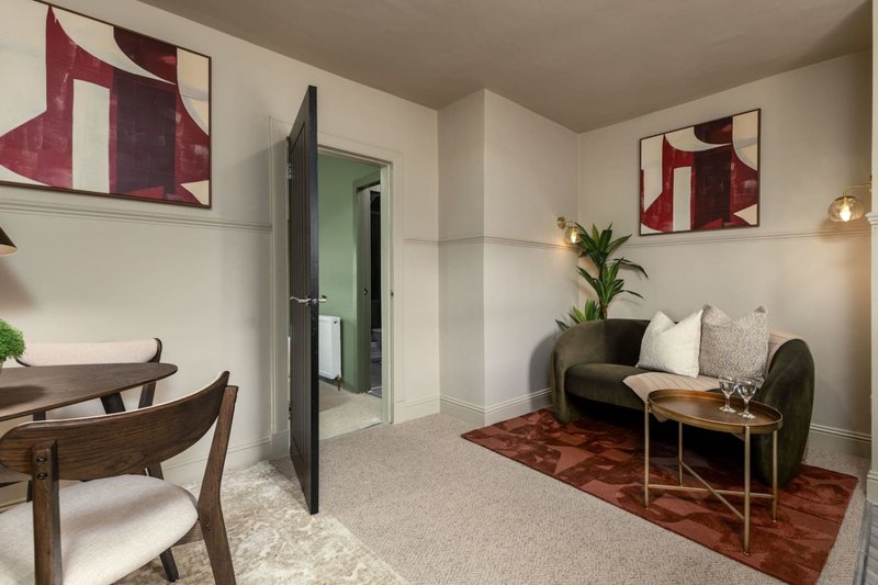 Modern living room with sofa, wooden chair, side table, and abstract wall art