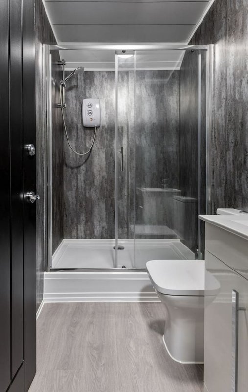 Modern bathroom with walk-in shower, toilet, sink vanity and gray tile walls