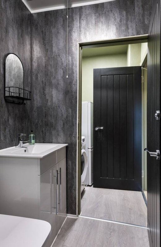 Modern bathroom with white vanity, toilet, sink, and black door to hallway