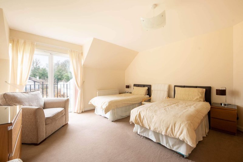 Twin bedroom with two single beds, armchair, and balcony access with garden views