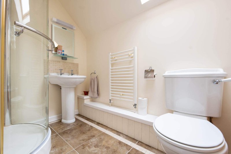 Bathroom with pedestal sink, toilet, bathtub with shower enclosure and towel rail