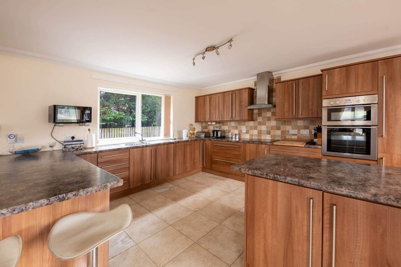 Large modern kitchen with wooden cabinets, granite countertops, integrated appliances and dining area
