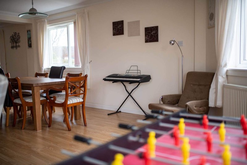 Open-plan living room with dining table, keyboard, foosball table and comfortable seating