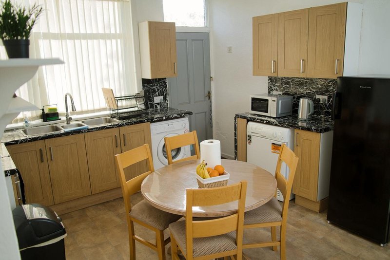Kitchen and dining area with wooden cabinets, round table, and four chairs