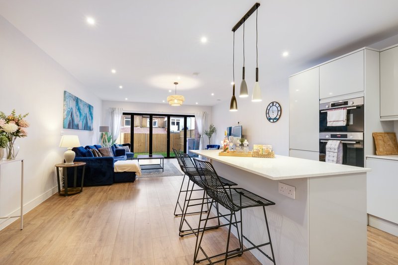 Open-plan kitchen and living area with white cabinetry, island seating, and blue sofa