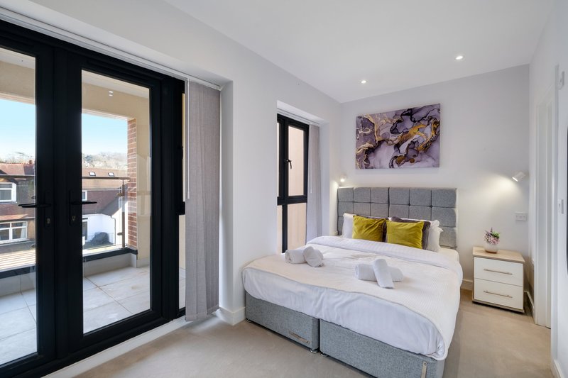 Modern bedroom with double bed, grey headboard, yellow cushions, and balcony access