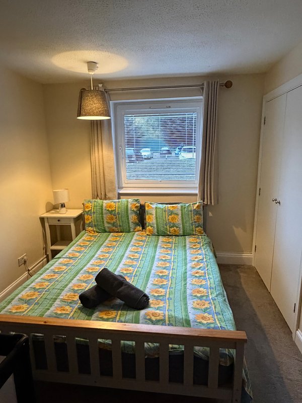 Bedroom with double bed, colorful patterned bedding, pendant lamp, and window with blinds