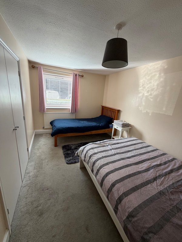 Shared bedroom with two single beds, wooden frame, pendant light, window with curtains