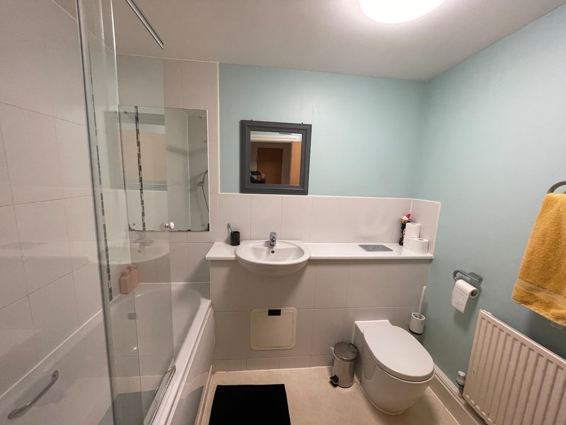 Modern bathroom with shower enclosure, pedestal sink, toilet and heated towel rail