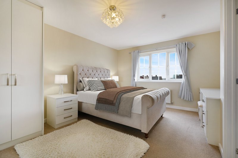 Spacious bedroom with upholstered bed, bedside tables, wardrobe and large window