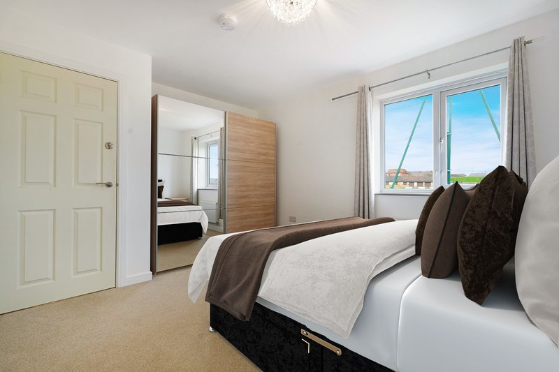 Bright bedroom with double bed, dark brown throw, ensuite bathroom and large window with countryside views