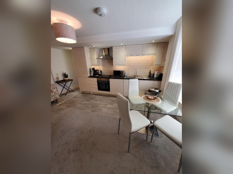 Open-plan kitchen and dining area with cream cabinetry, dining table, and living space