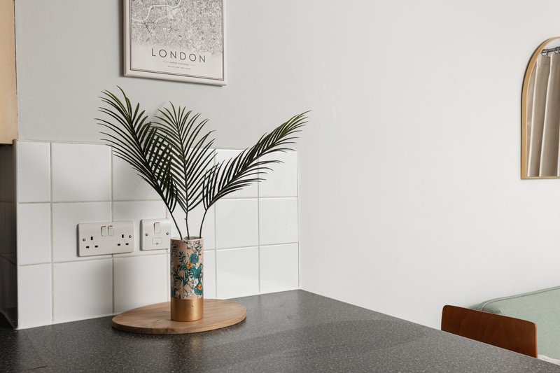 Modern kitchen counter with dark worktop, potted plant, and white tile backsplash