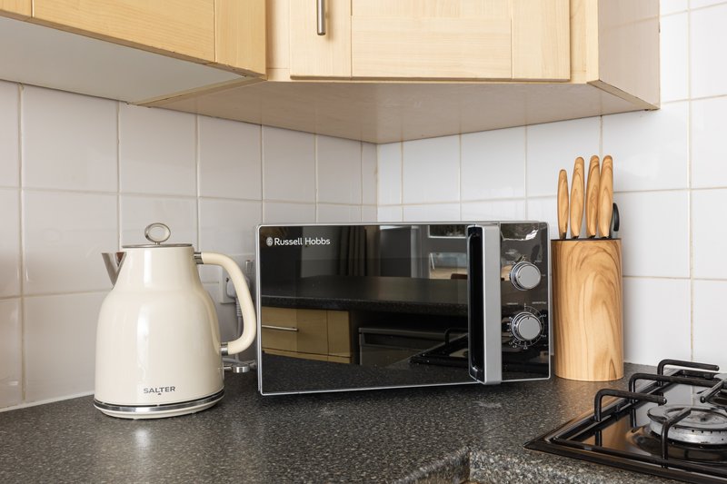 Kitchen countertop with microwave, kettle, knife block and stovetop