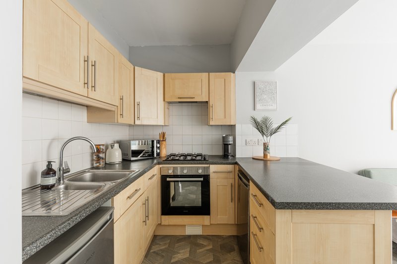 Modern kitchen with wooden cabinets, granite countertops, stainless steel appliances and white tile backsplash