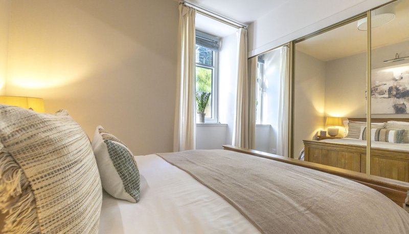 Bright bedroom with double bed, mirrored wardrobe, and window with natural light