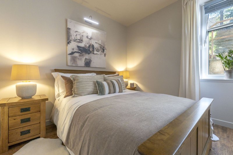 Modern bedroom with double bed, wooden furniture, bedside lamps and wall art