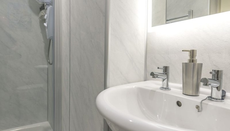 Modern bathroom with white sink, chrome fixtures, mirror and shower enclosure