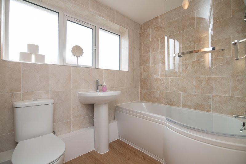 Clean bathroom with toilet, pedestal sink, bathtub and window