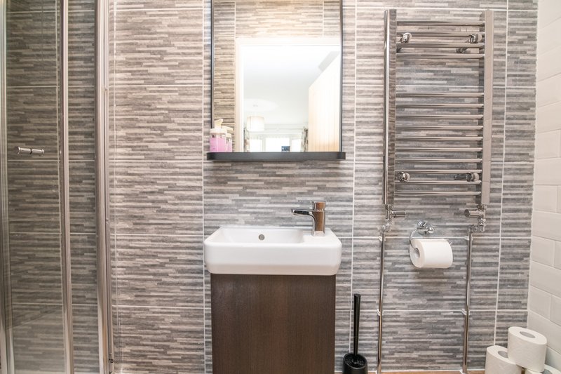 Modern bathroom with striped tile walls, floating vanity sink, mirror and towel rails