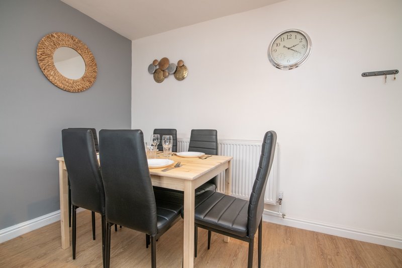 Dining room with wooden table, black chairs, wall clock and decorative items