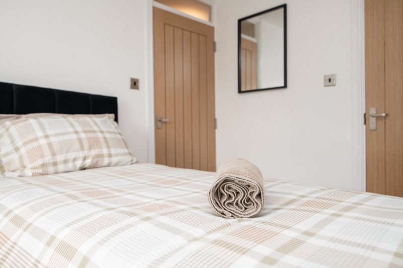 Bedroom with double bed, patterned bedding, black headboard, wooden doors and mirror